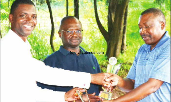 Blantyre Sports Club vice chair Justice John Katsala (right) presents trophy to winners Makhwawa and Chapola (centre)