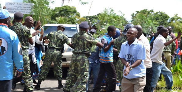 Police officers at the southern region police headquarters try to give way to a vehicle carrying Malawi's former president's brother, Arthur Peter Mutharika, to enter into police headquarters in Blantyre on March 11, 2013.