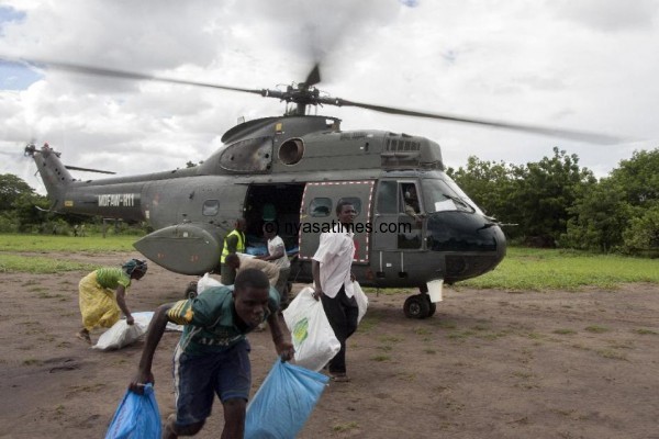 People unload flood relief aid from a Malawi military helicopter as it arrives at M'bwazi Primary School in the southern Nsanje district on January 18, 2015 (AFP Photo/Amos Gumulira)