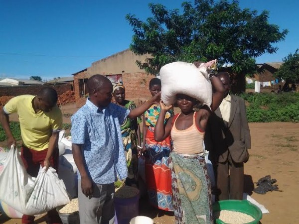 Chisomo Children's Club Executive Director Charles Gwengwe distributing maize to hunger striken women in Lilongwe