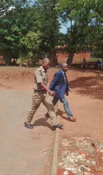 Mtumodzi accompanied by police officer on arrival at court - Photo by Mphatso Nkhoma, Nyasa Times: