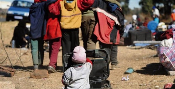 A child plays in an abandoned suitcase near the Lindela resettlement camp  where hundreds of Malawi nationals are etained