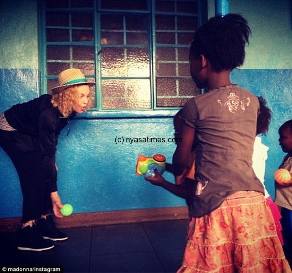 Back in favour: Madonna shared this picture showing her playing with young Malawian country after arriving in the central African country for the first time since falling out with the former president in April last year