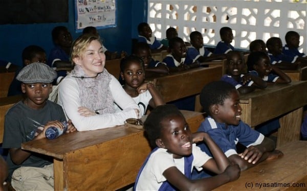 Madonna sits with David Banda, to her left, and Mercy James in a classroom of the Mkoko Primary School Photo: AFP