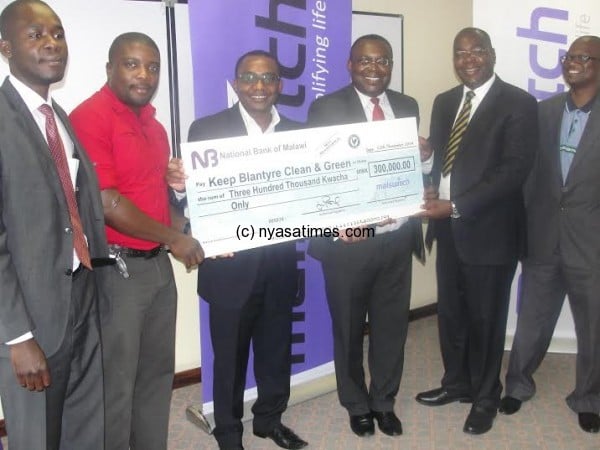 Kamkwalala (third left) presents a dummy cheque to Msusa (second left) and Mijiga (middle) while other Malswitch managers look on.