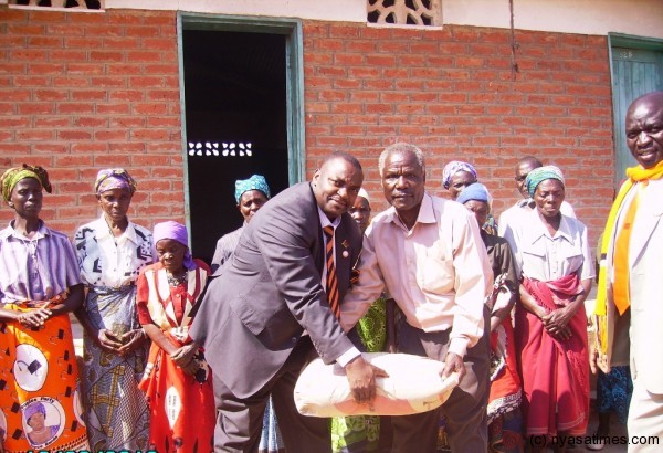 Mtonga presenting a bag of cement to the community