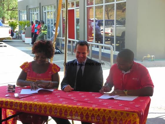 Total Malawi managing director (suit) and Chilima  during the signing ceremony