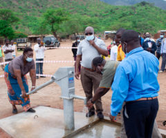 Mkango country administrator Effie Likaku pumps water from newly launched borehole as country director Kachinjika looks on