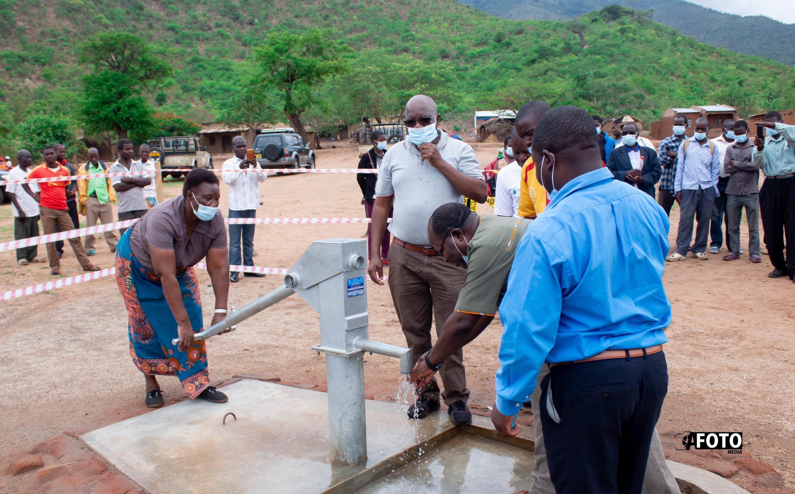 Mkango country administrator Effie Likaku pumps water from newly launched borehole as country director Kachinjika looks on